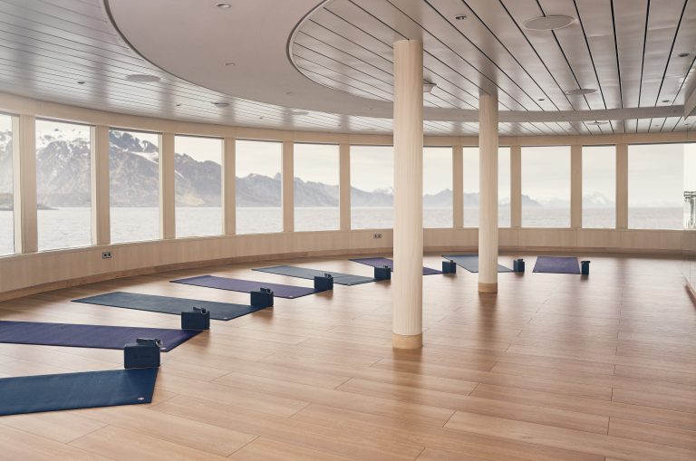 National Geographic yoga studio with yoga mats on wood floor and many large windows.